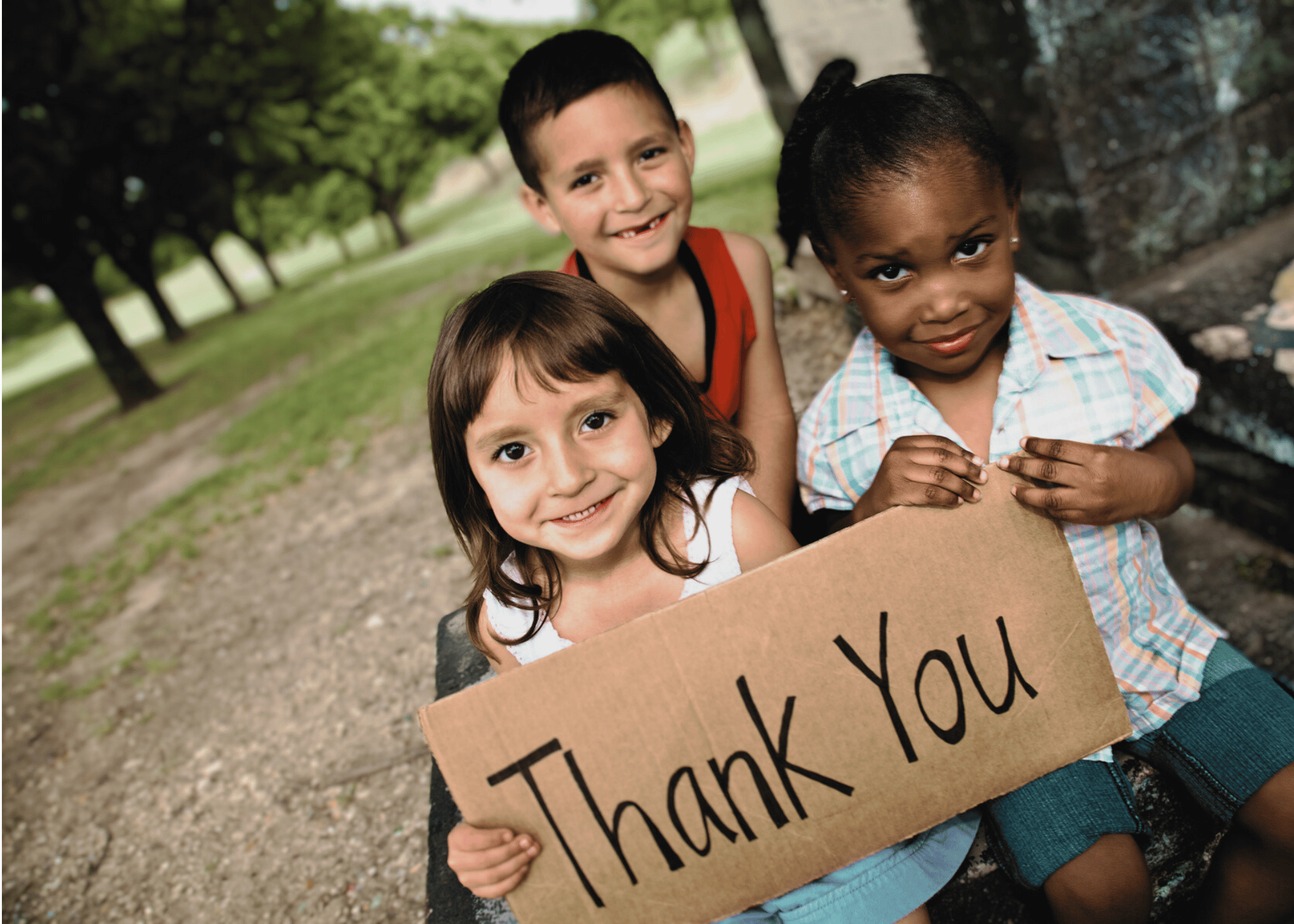 Drei Kinder halten ein Schild mit der Aufschrift „Danke“