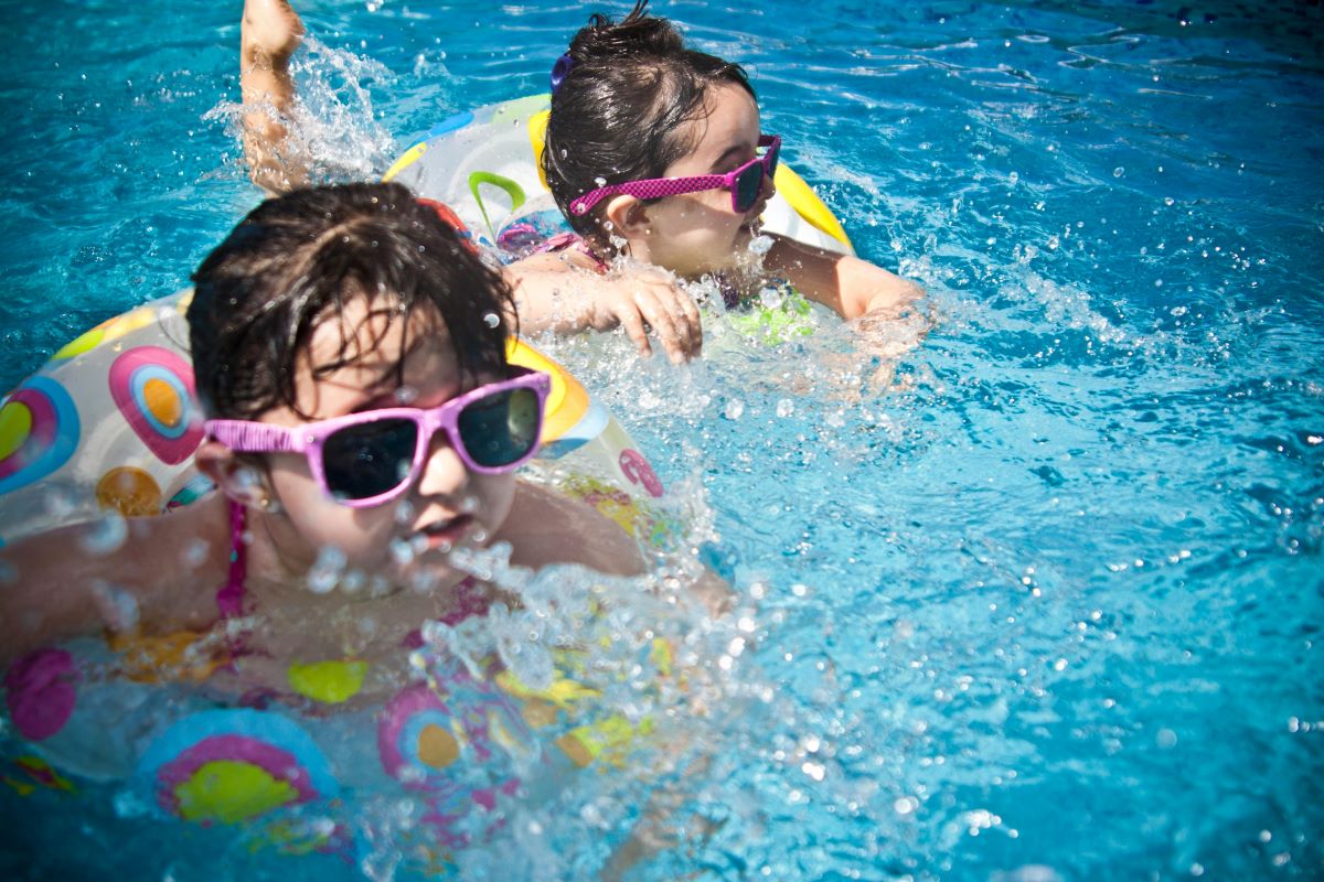 Two girls swimming in pool in floatie rings.