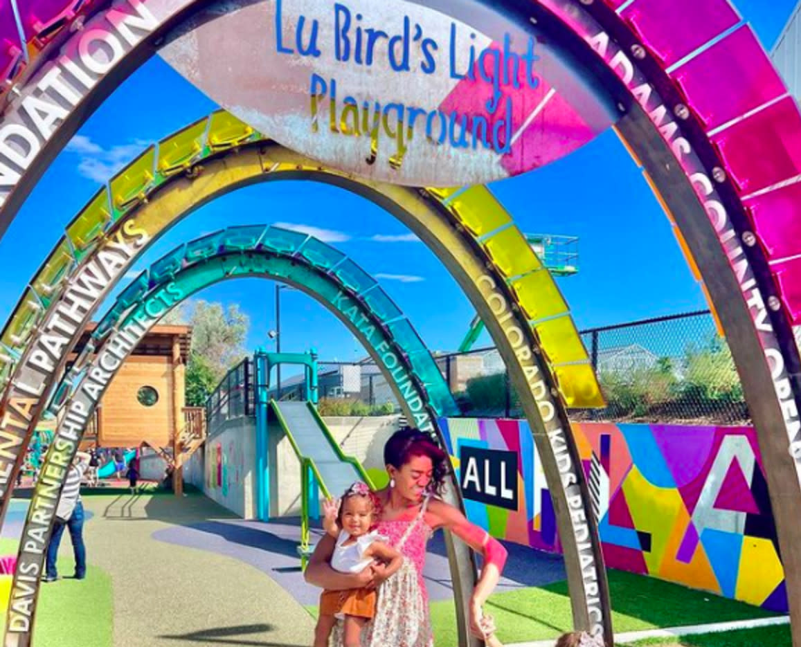 Adult with child under rainbow arch at LuBird's Playground