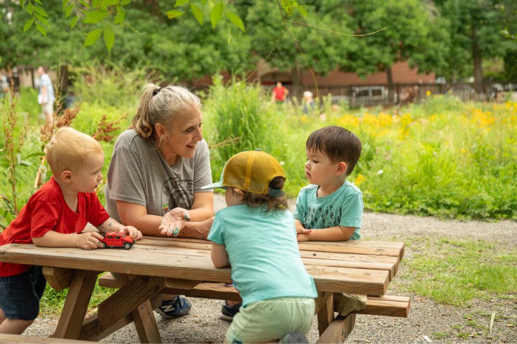 Teacher with students outdoors at picnic table