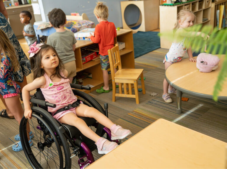 Fille d'âge préscolaire en fauteuil roulant à son bureau