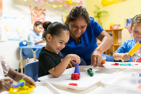 Maestra ayudando a niña de preescolar con bloques