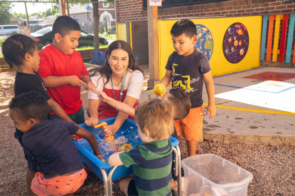 Preschool teacher and children at water table