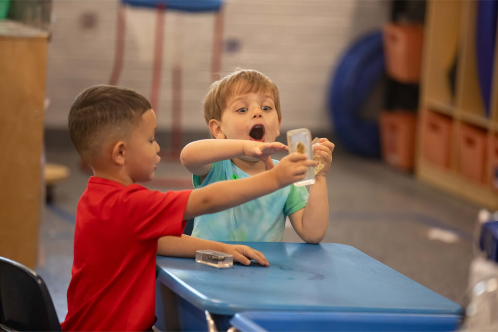 Dois meninos em idade pré-escolar juntos em uma sala de aula.