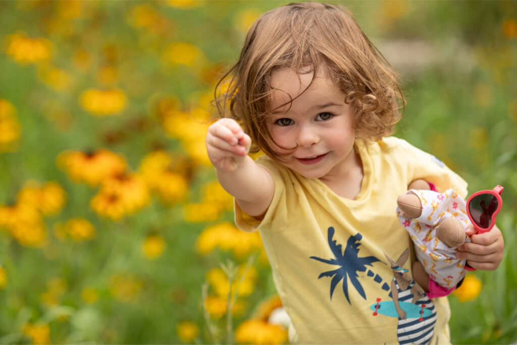 Jeune fille dans un champ de fleurs regardant la caméra.