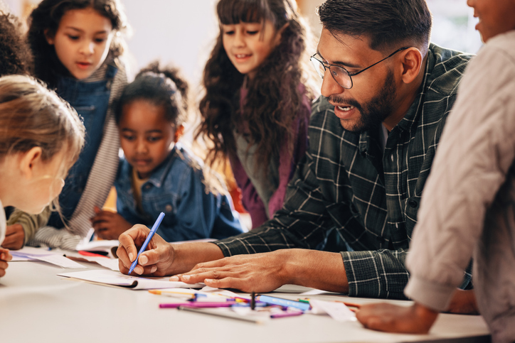 Homem ensina seus alunos a desenhar em uma aula do ensino fundamental.