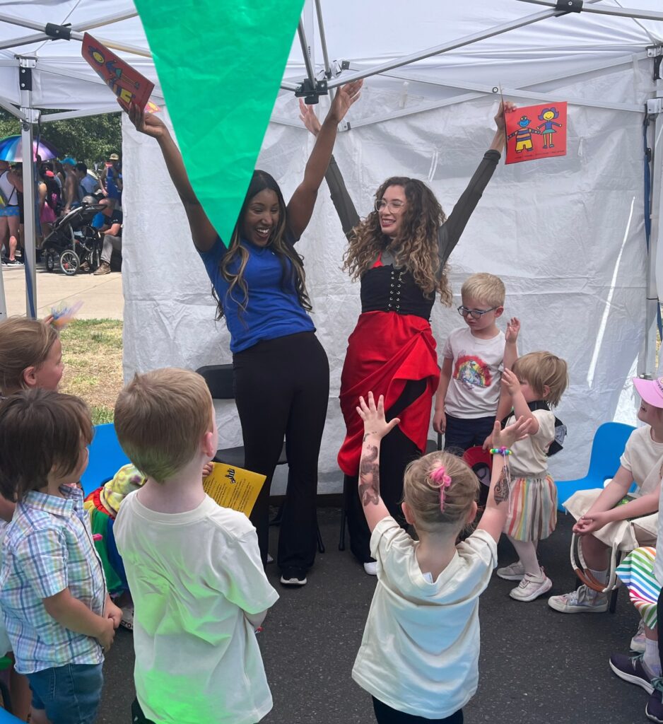 Two women raising hands at book reading with little kids