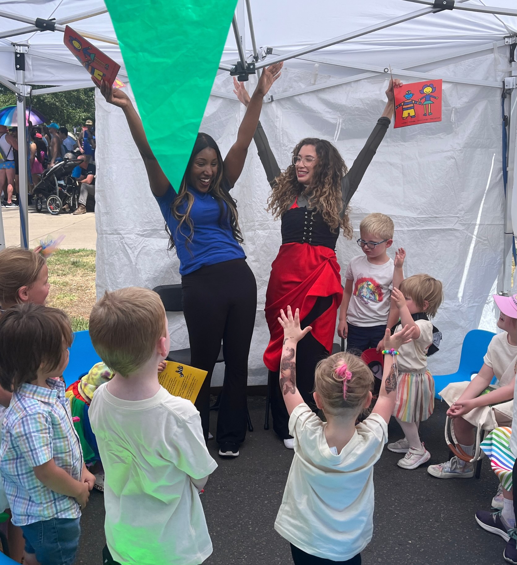Two women raising hands at book reading with little kids
