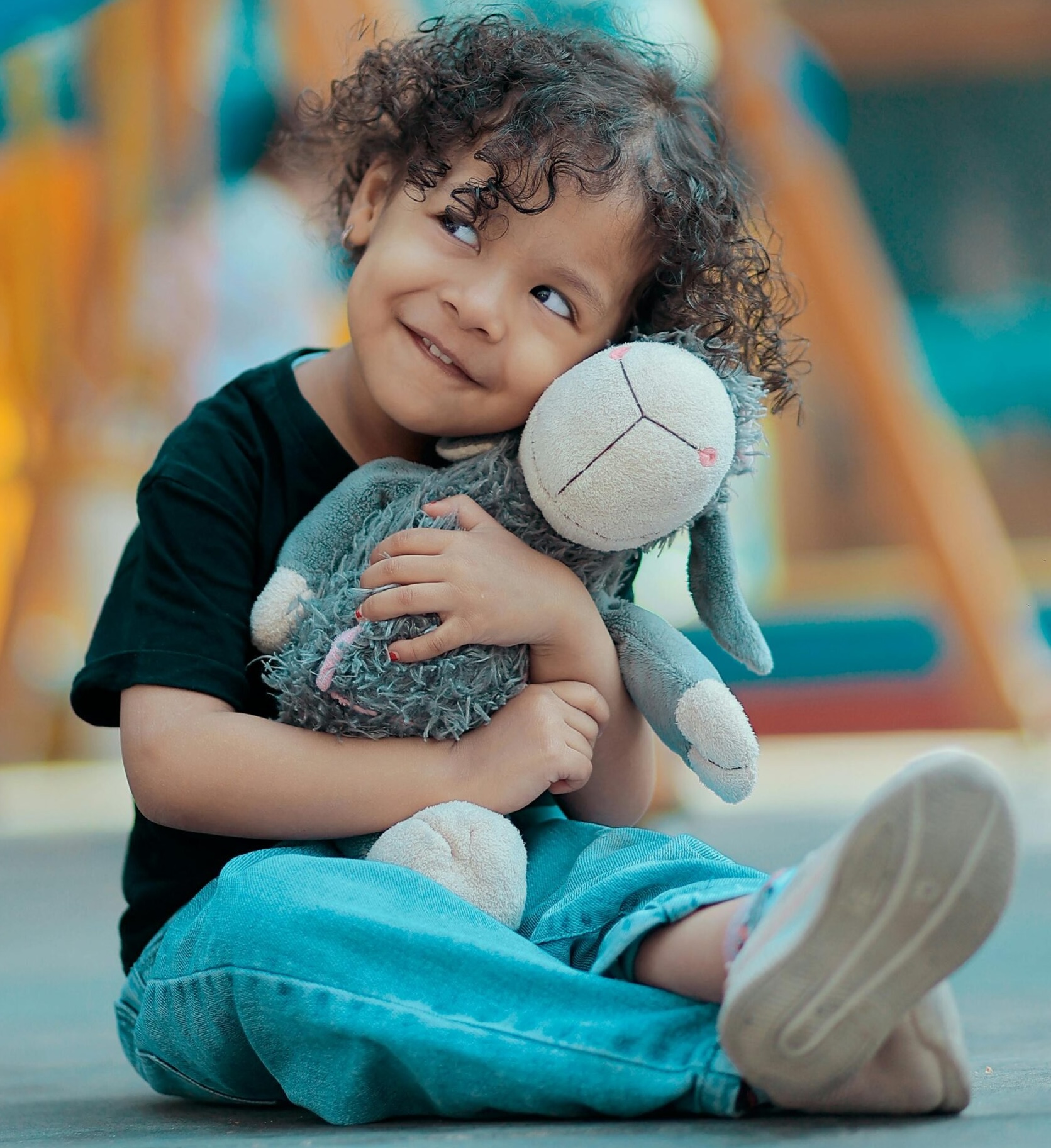 Garçon souriant et serrant sa peluche dans ses bras dans l'aire de jeux
