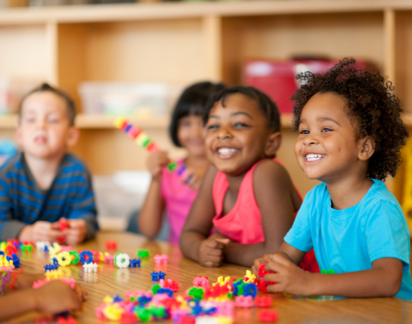 Children smiling with play blocks in front of them