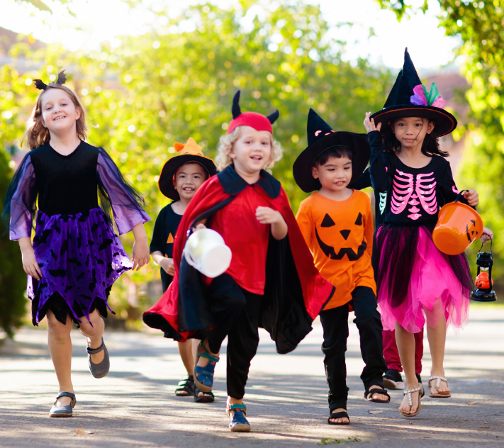 children dressed in Halloween costumes running down the street