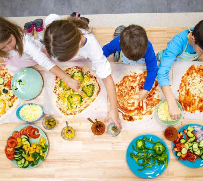 Four young children making pizzas