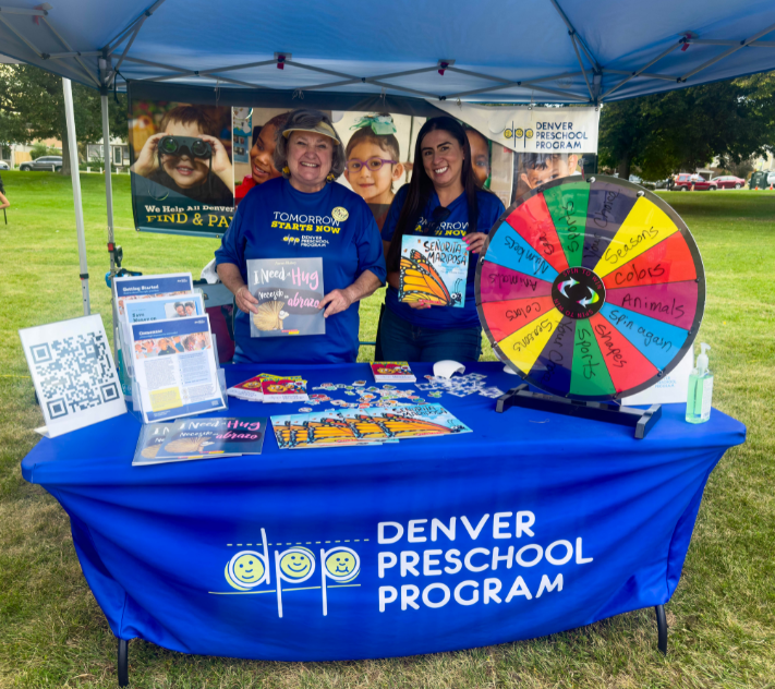 Two women standing in front of table at a park