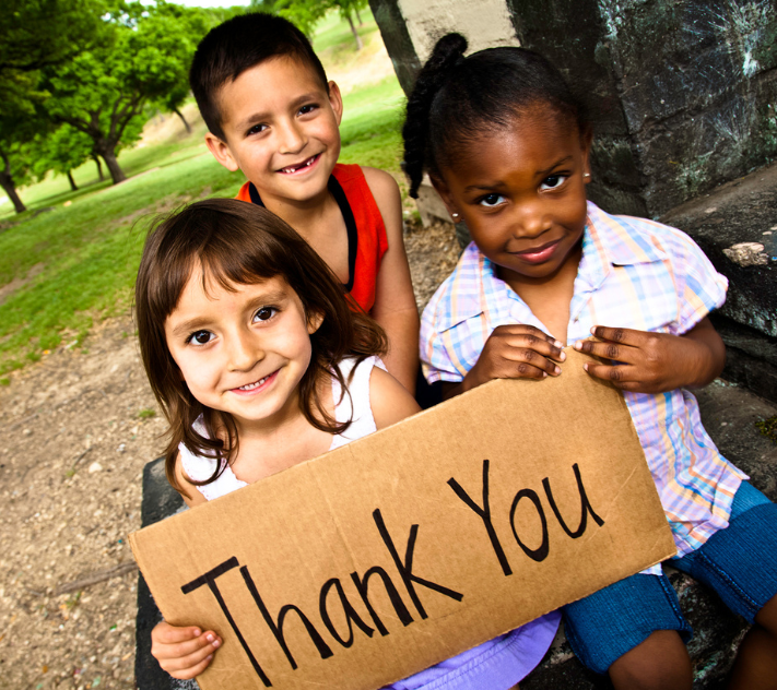 Three young children holding a sign that says "Thank you"