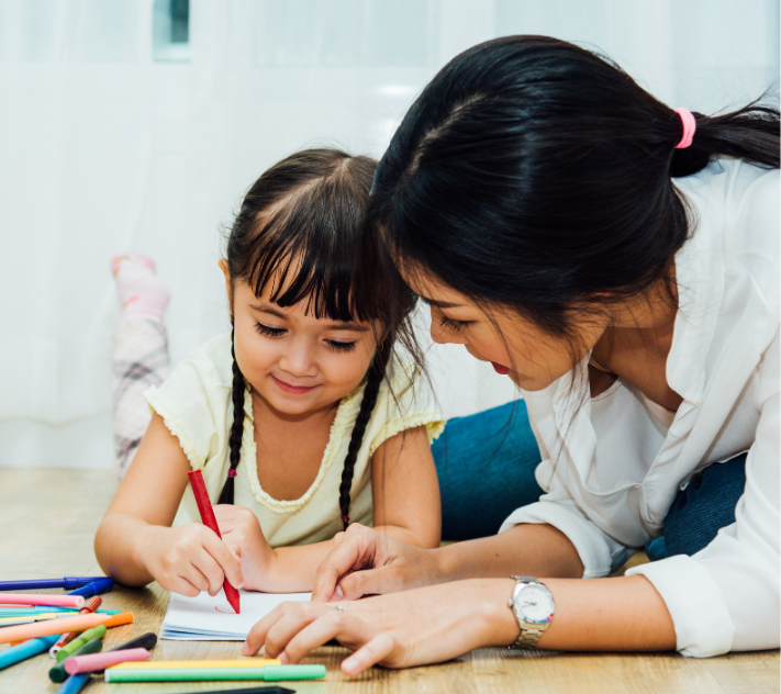 Маленькая девочка раскрашивает вместе с мамой