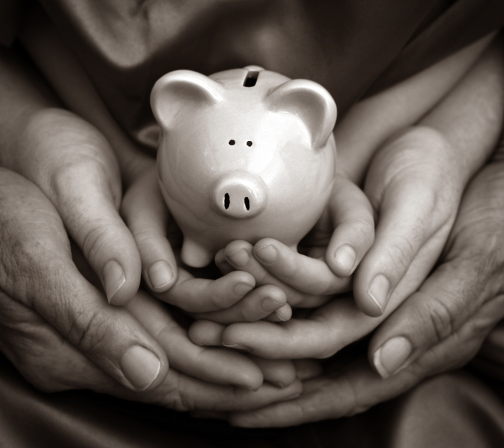 Parents and children's hands holding a piggy bank.