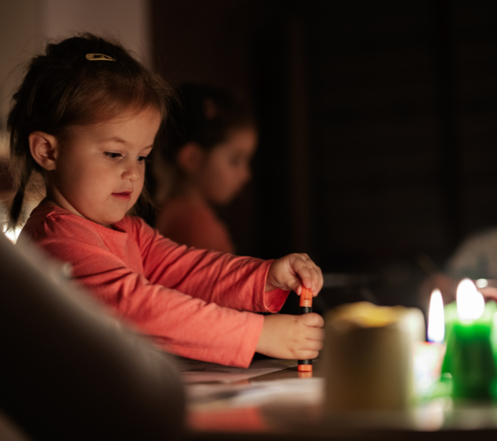 数本のろうそくの明かりで暗闇の中で遊ぶ少女。