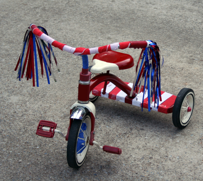 Tricycle decorated in red and white stripes with blue streamers.