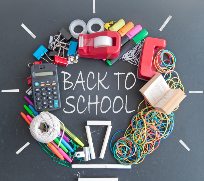 School supplies in a circle with "back to school" written with chalk in the middle.