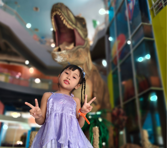 Junges Mädchen steht vor einer Dinosaurierstatue